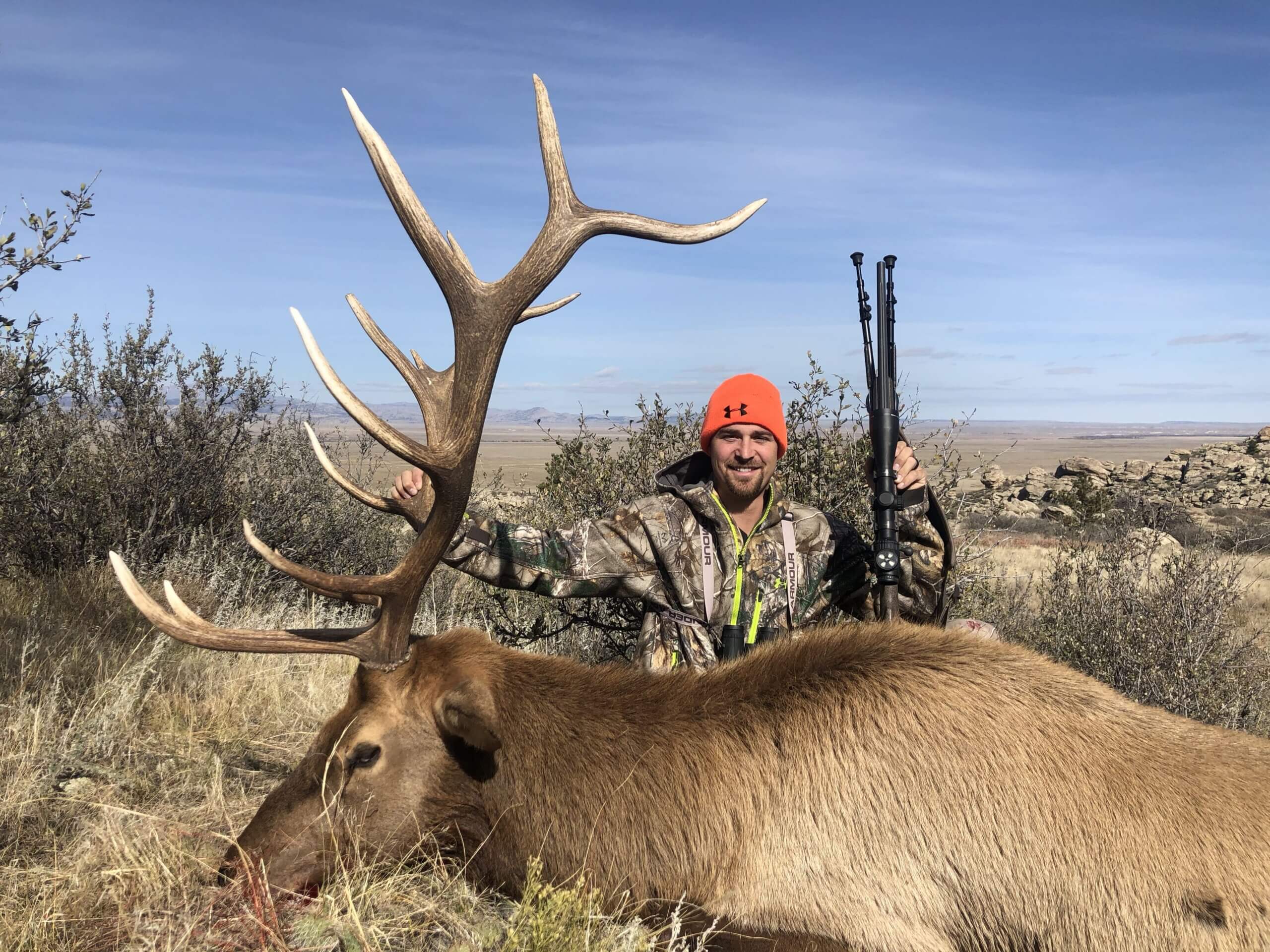 Man with an elk and hunting rifle in a field