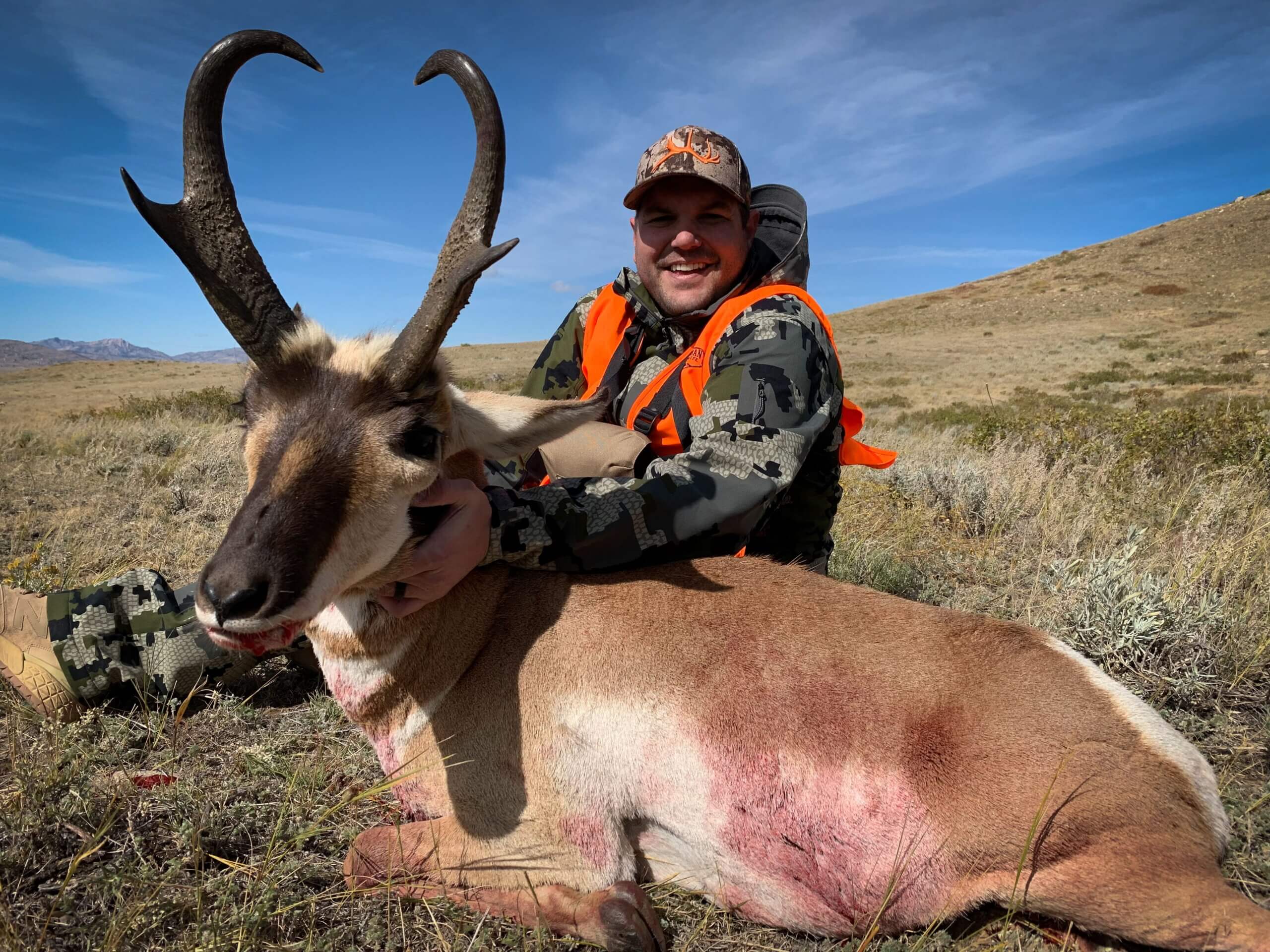 Hunter holding a large antelope in a desert landscape