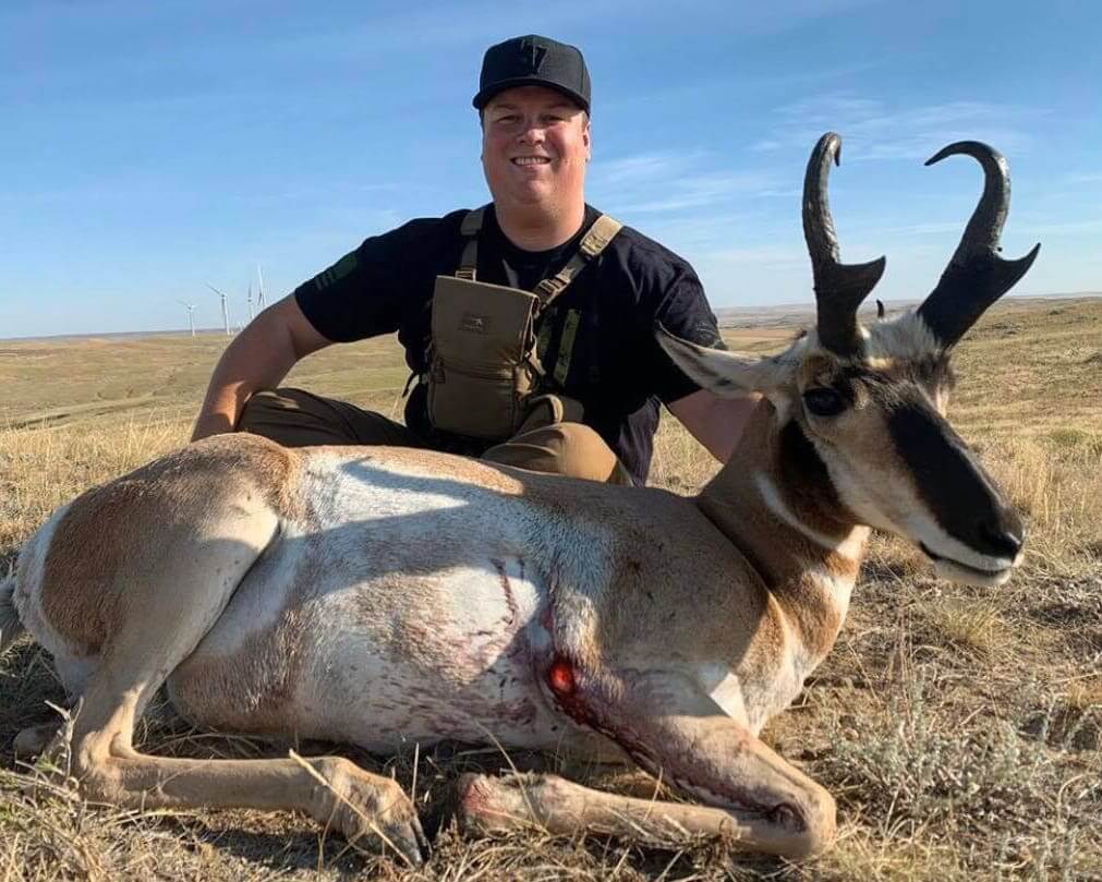 Man posing with a large antelope in a field