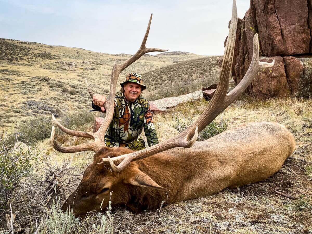 Hunter with a large elk in a natural landscape